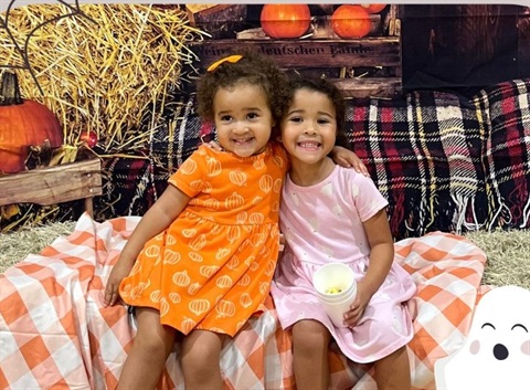 two girls behind a fall backdrop