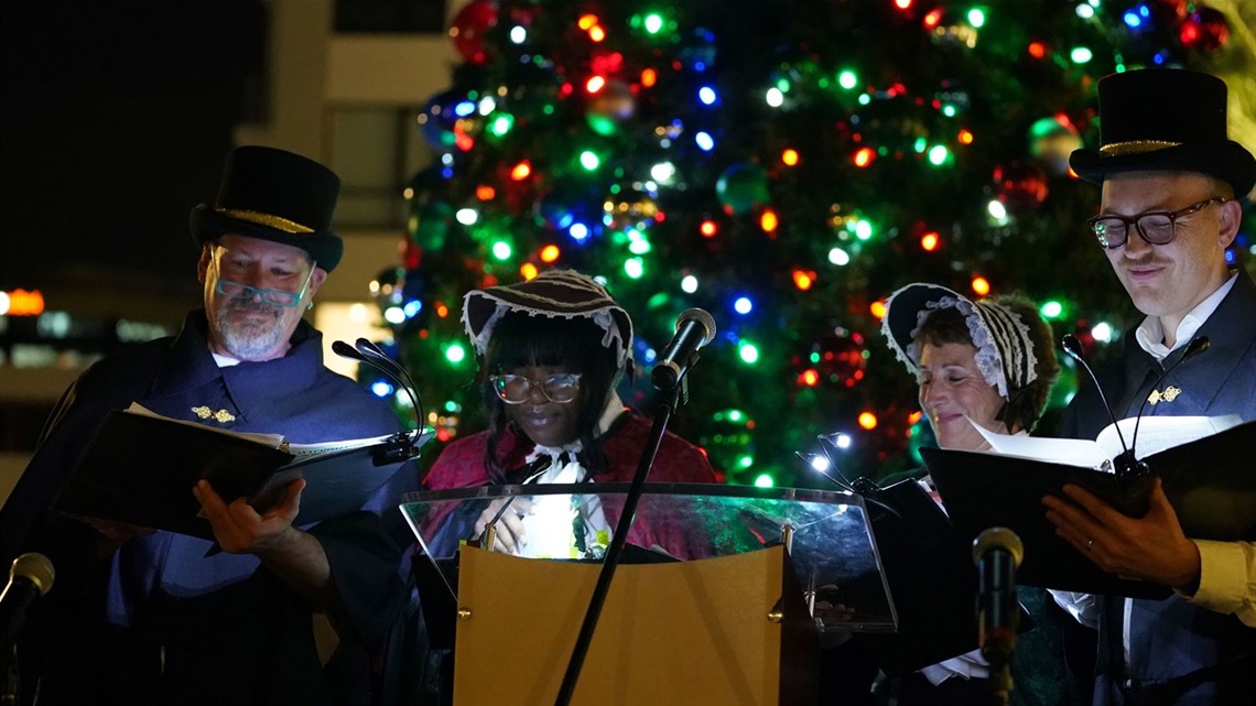 carolers in front of a tree