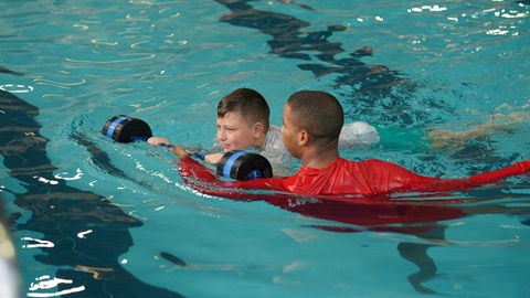boy learning to swim with lifeguard